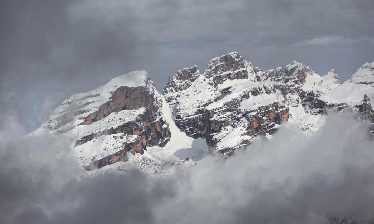 Snow-capped mountains peek through the cloudy sky.