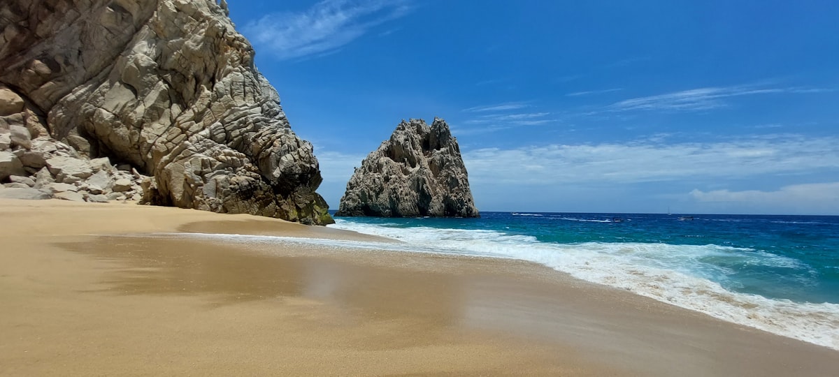 brown rocky mountain beside blue sea under blue sky during daytime