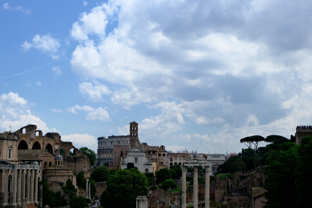 Ancient roman ruins under a cloudy blue sky.
