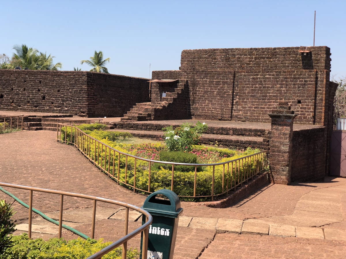 green metal fence near brown brick wall