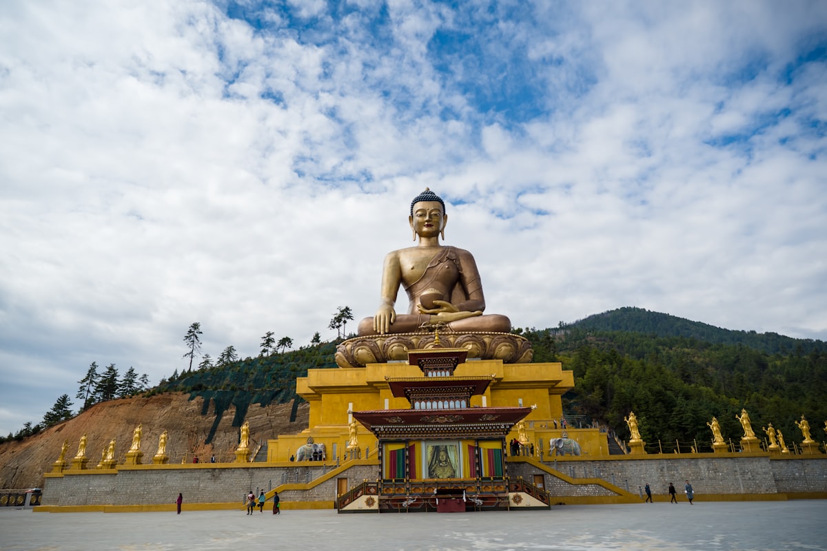 brown concrete statue under white clouds and blue sky during daytime