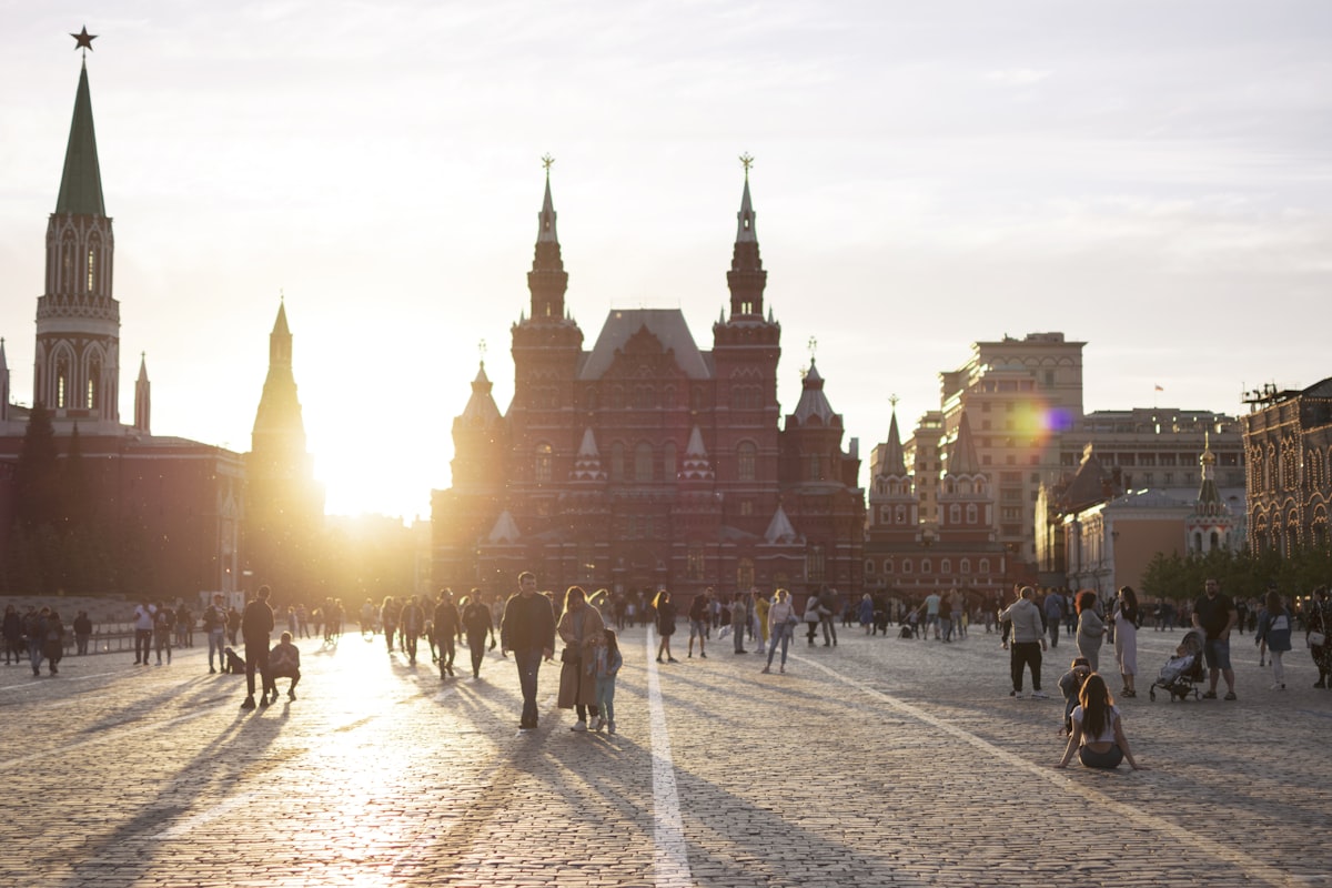 a group of people walking in a plaza with buildings in the background