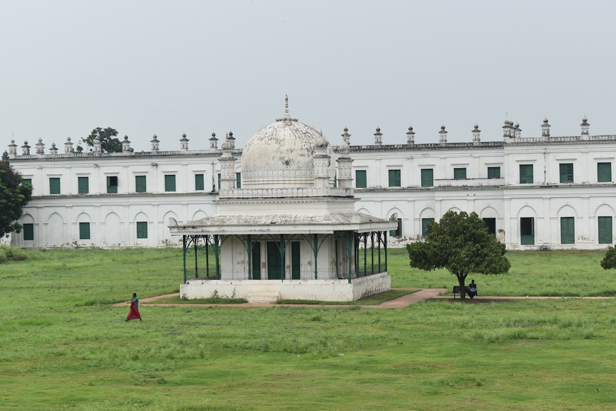 a large white building with a green field in front of it