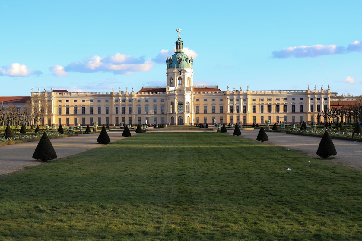 people walking on green grass field near white concrete building during daytime