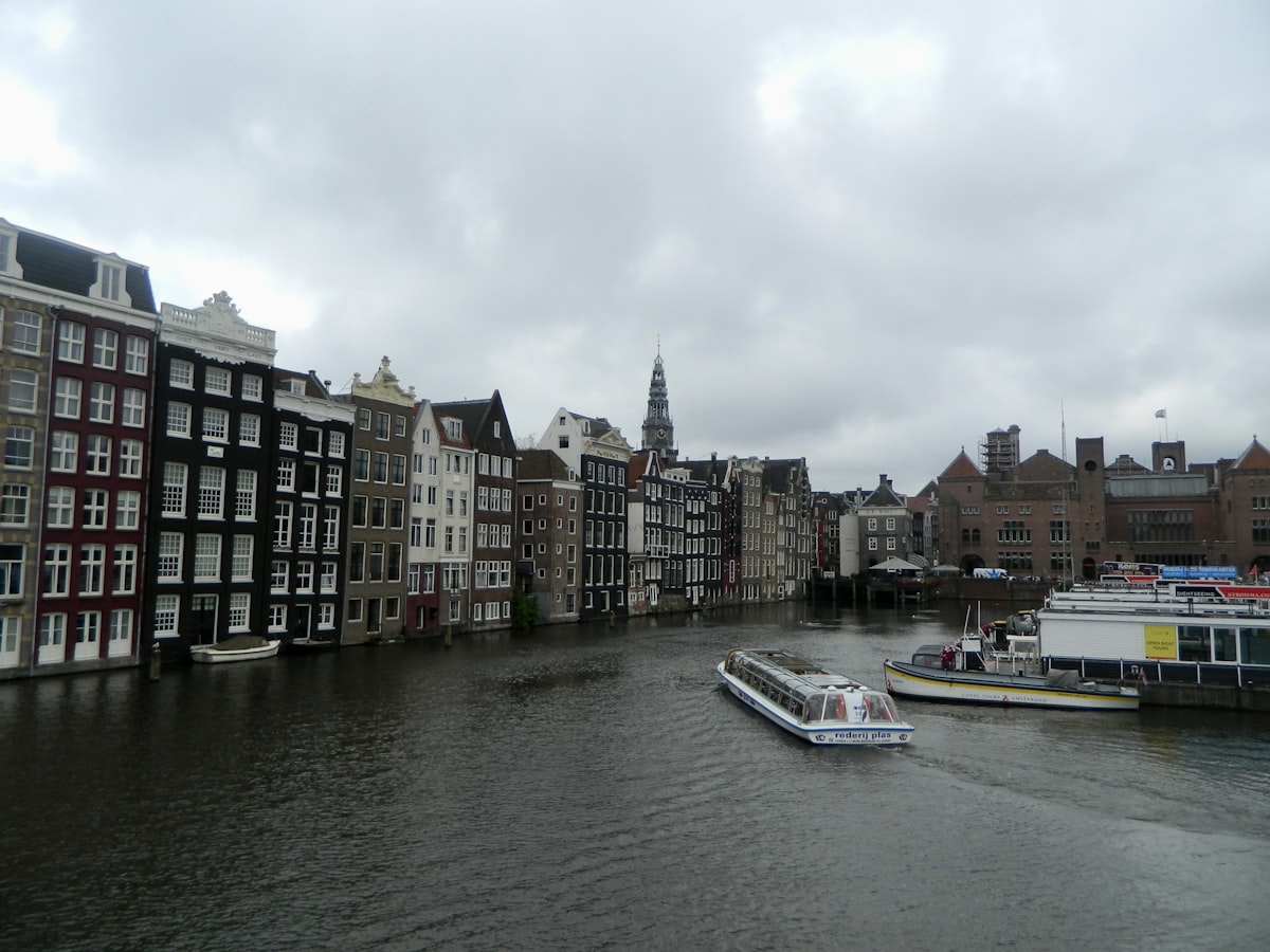 a boat traveling down a river next to tall buildings