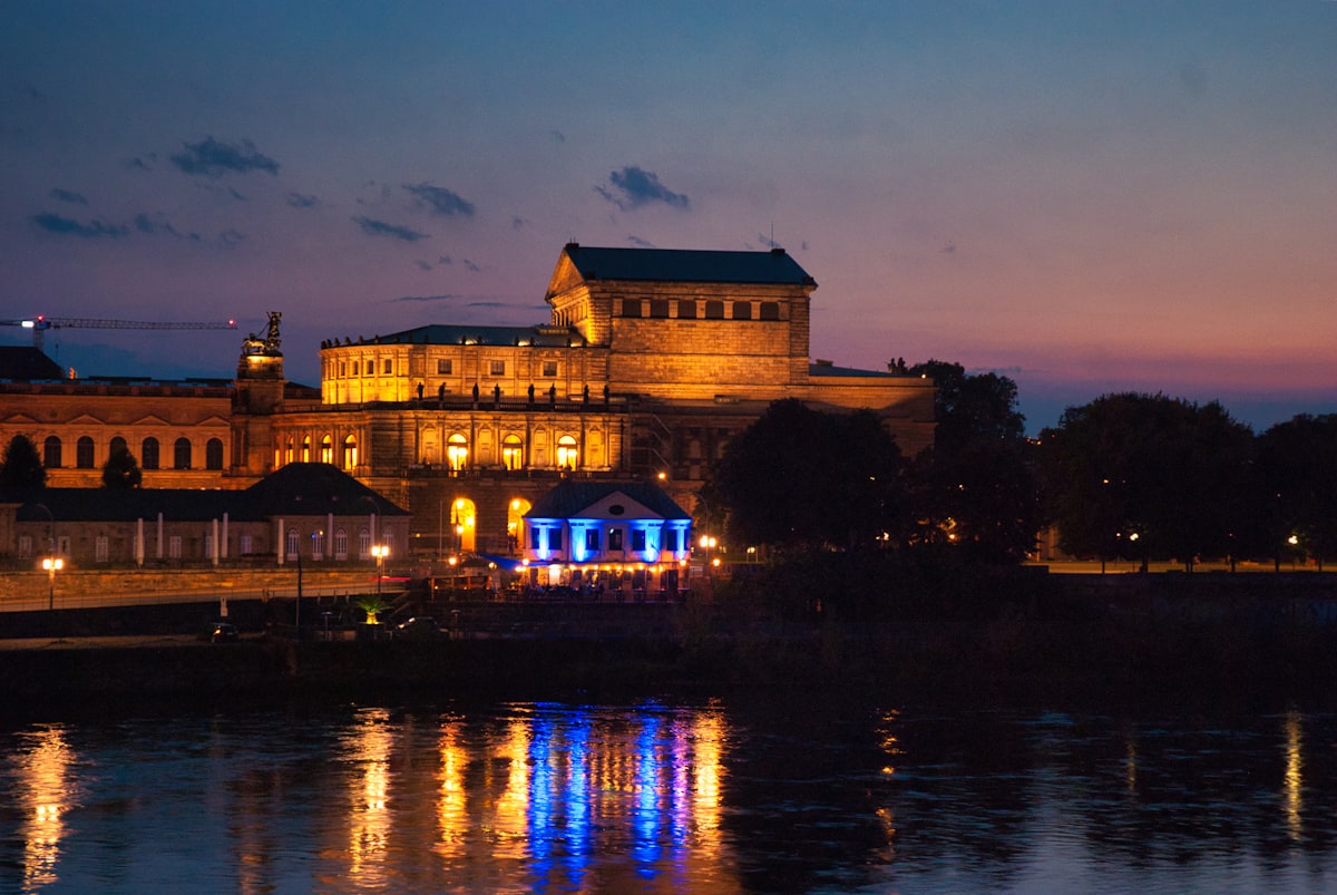 City buildings illuminated at night with water reflection.