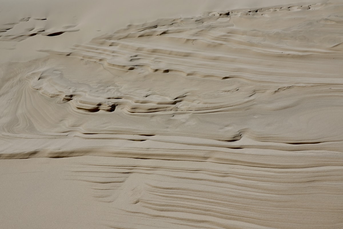A person riding a surfboard on top of a sandy beach