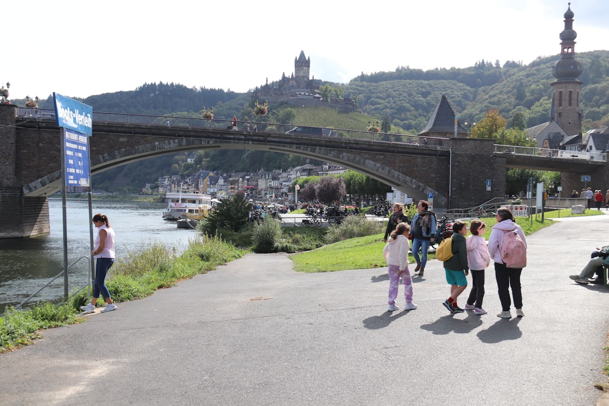 a group of people walking down a road next to a river
