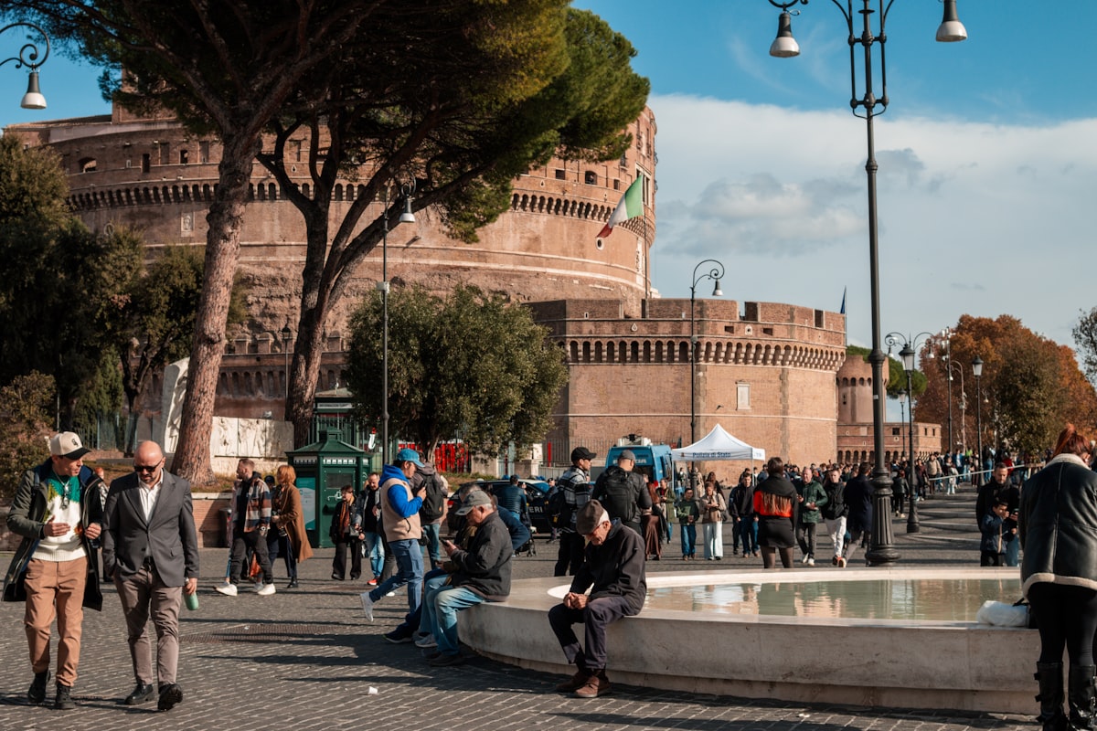 People gathered near a historic circular building with trees.