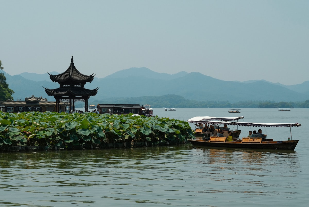 A boat floating on top of a lake next to a tall building
