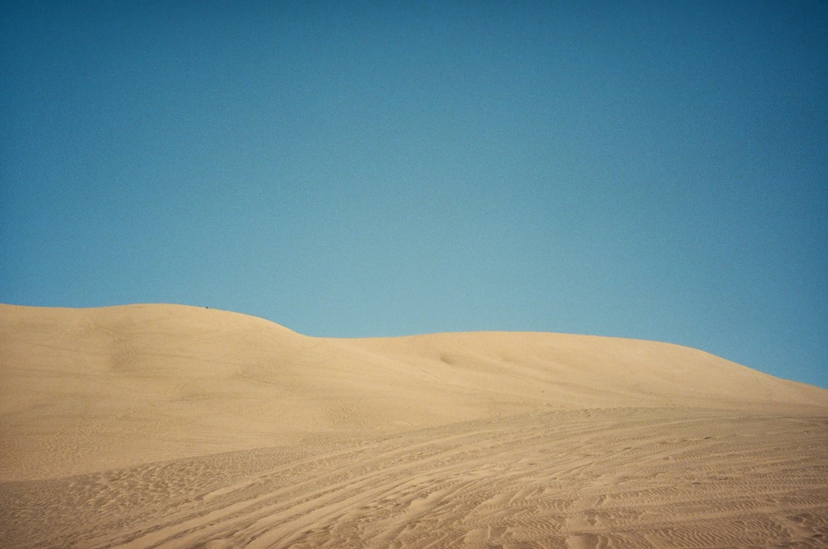 A large sand dune with a blue sky in the background