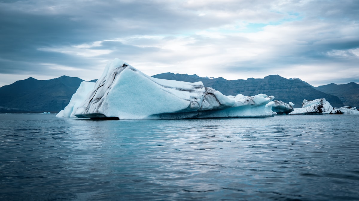 Large iceberg floating in the ocean under cloudy sky