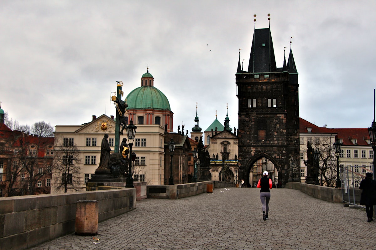 a person walking across a bridge with a clock tower in the background