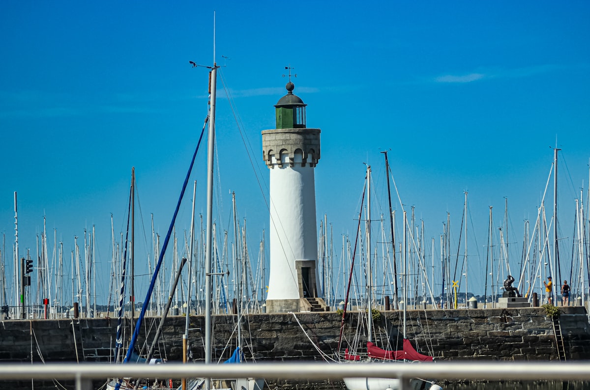a lighthouse surrounded by sailboats in a harbor