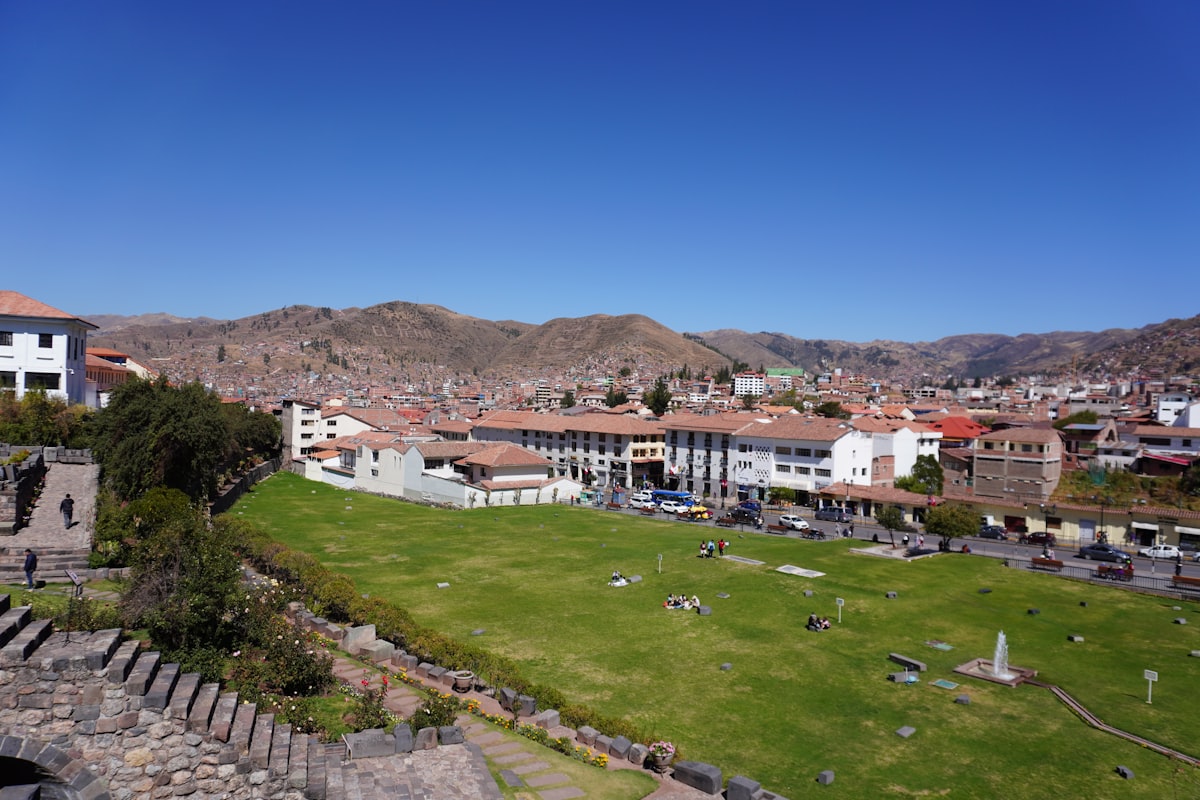 An aerial view of a city with a green field in the foreground