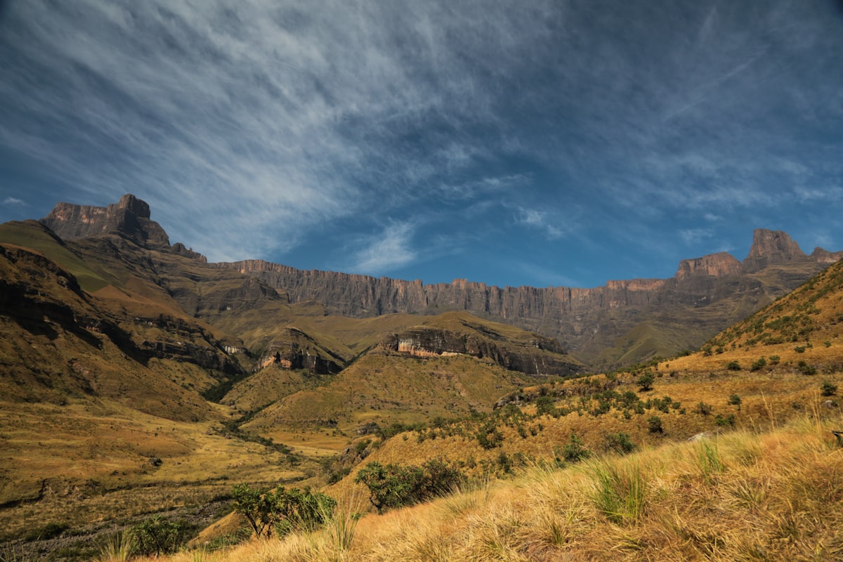 aerial photography of green filed viewing mountain under blue and white sky during daytime