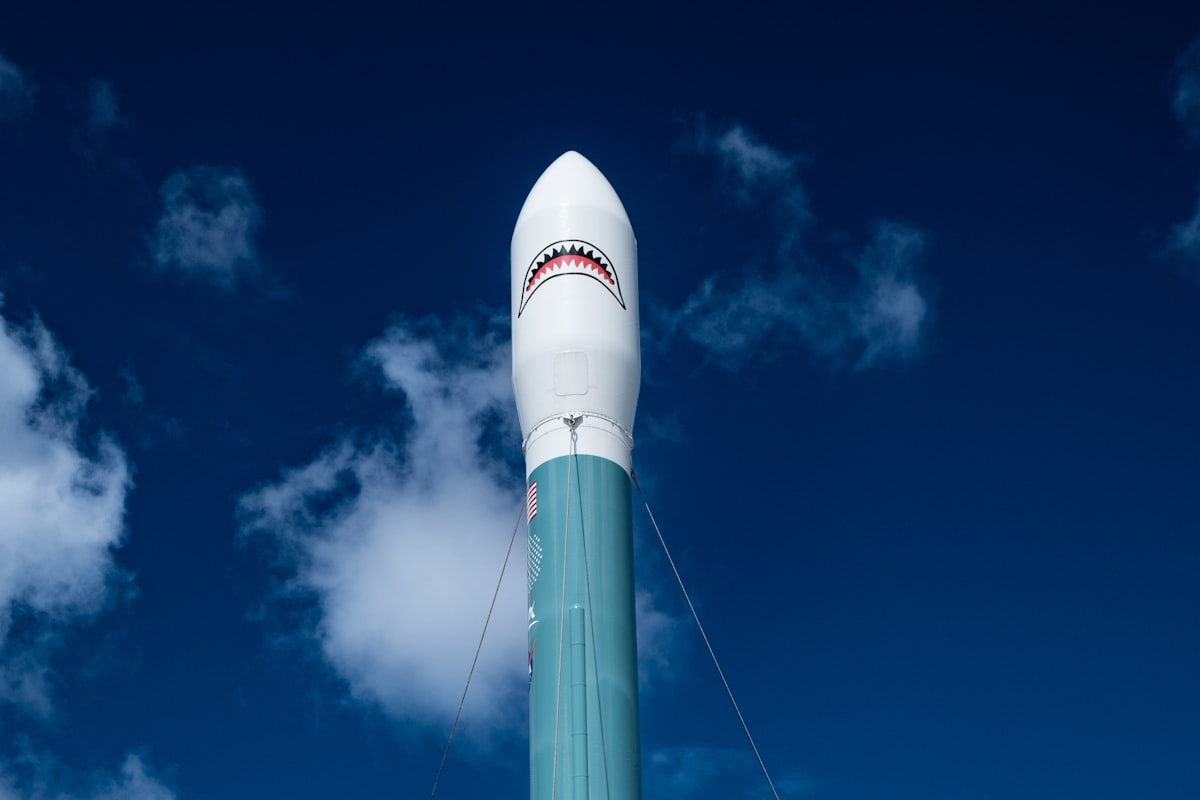 A white and blue rocket with a shark on it