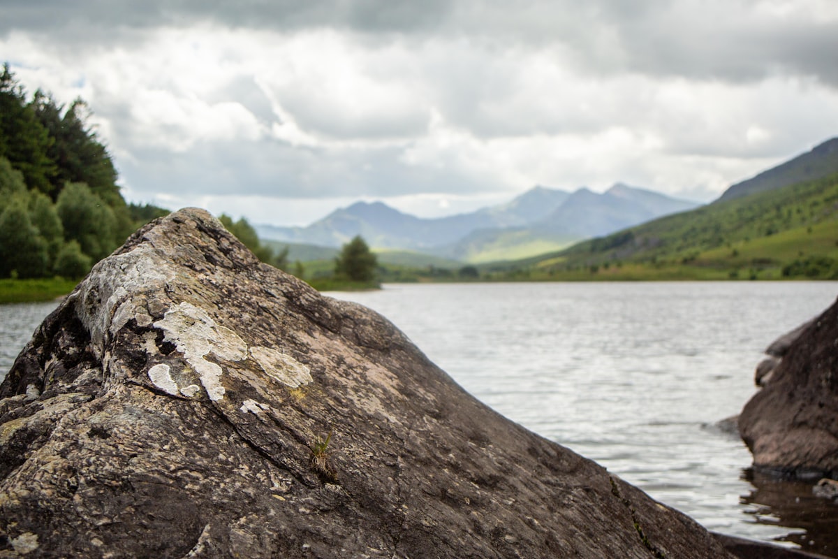 Lake surrounded by green hills and mountains under clouds