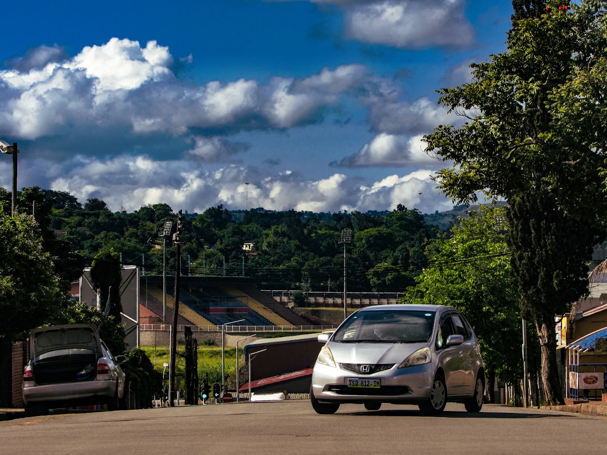 A car drives down a street with stadium in view.