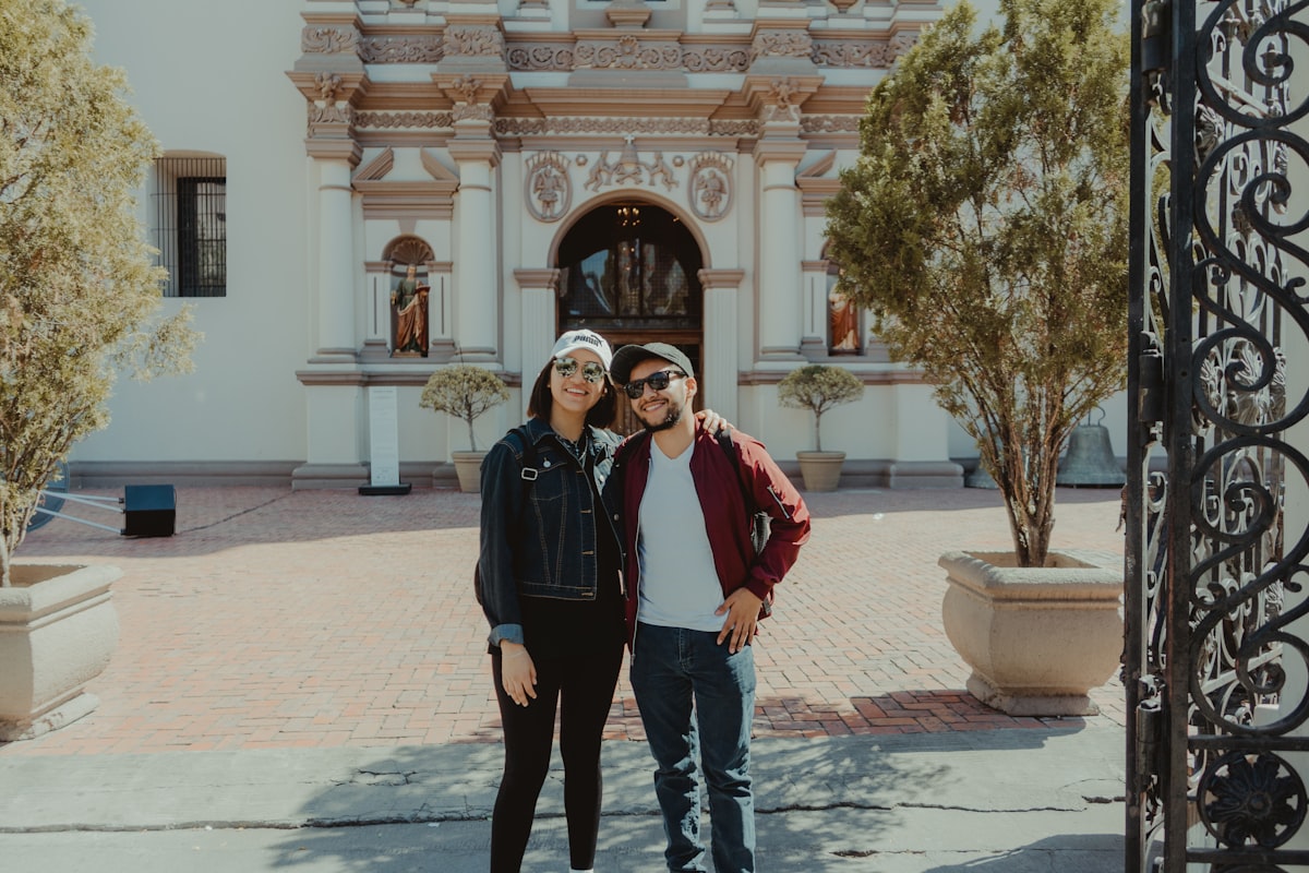 man in black jacket standing beside woman in red coat