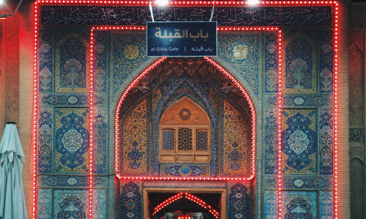 Ornate building entrance with intricate tilework and red lights.