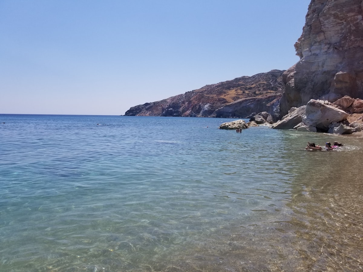 a body of water next to a rocky cliff
