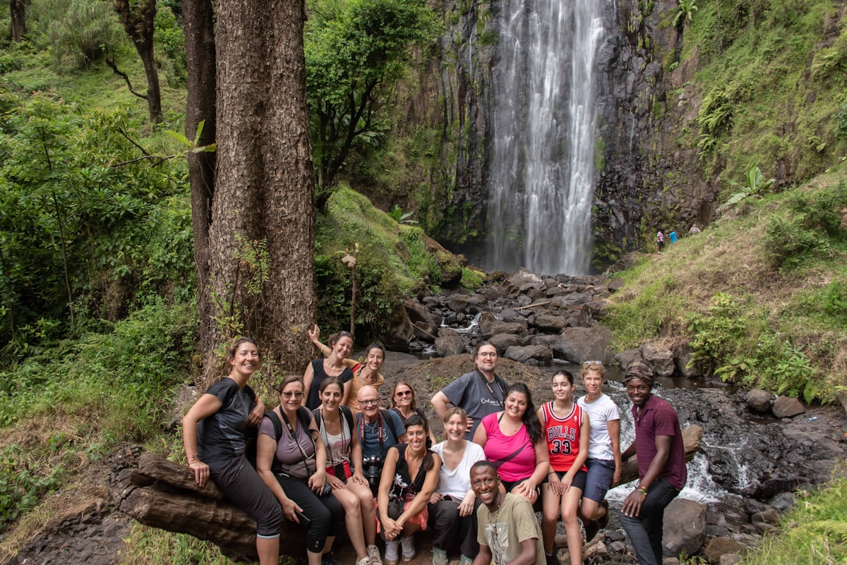 A group of people posing in front of a waterfall.
