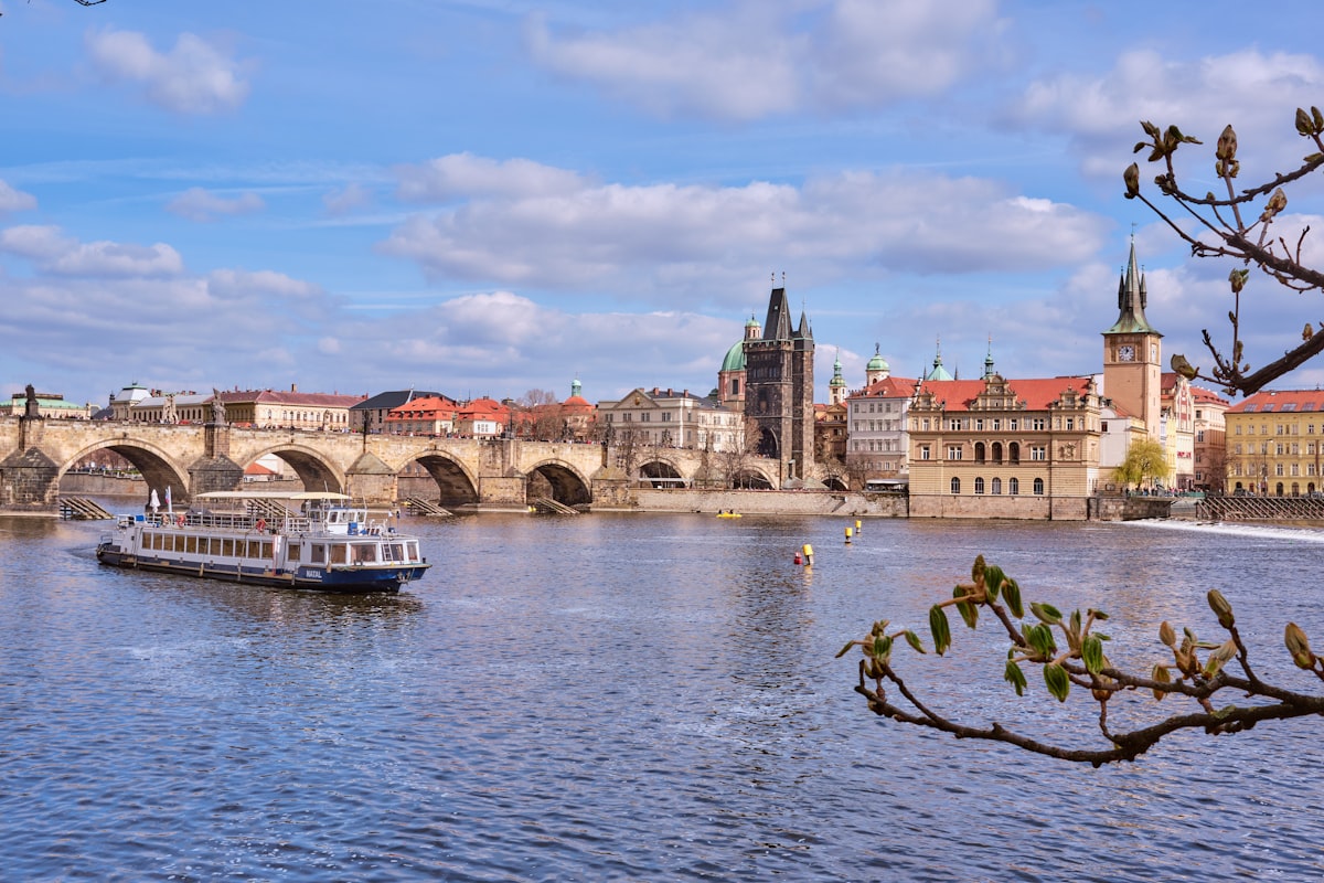 A boat traveling down a river next to a bridge