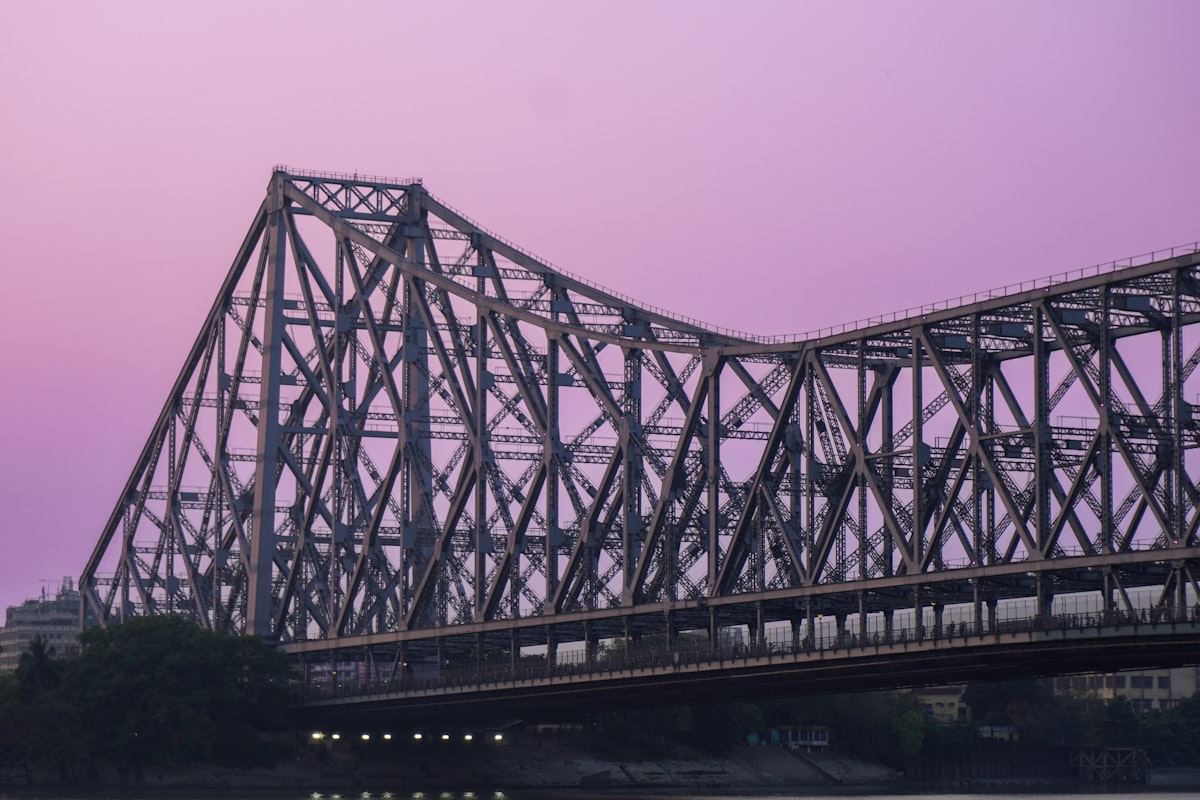 Howrah bridge stands against a purple sky.