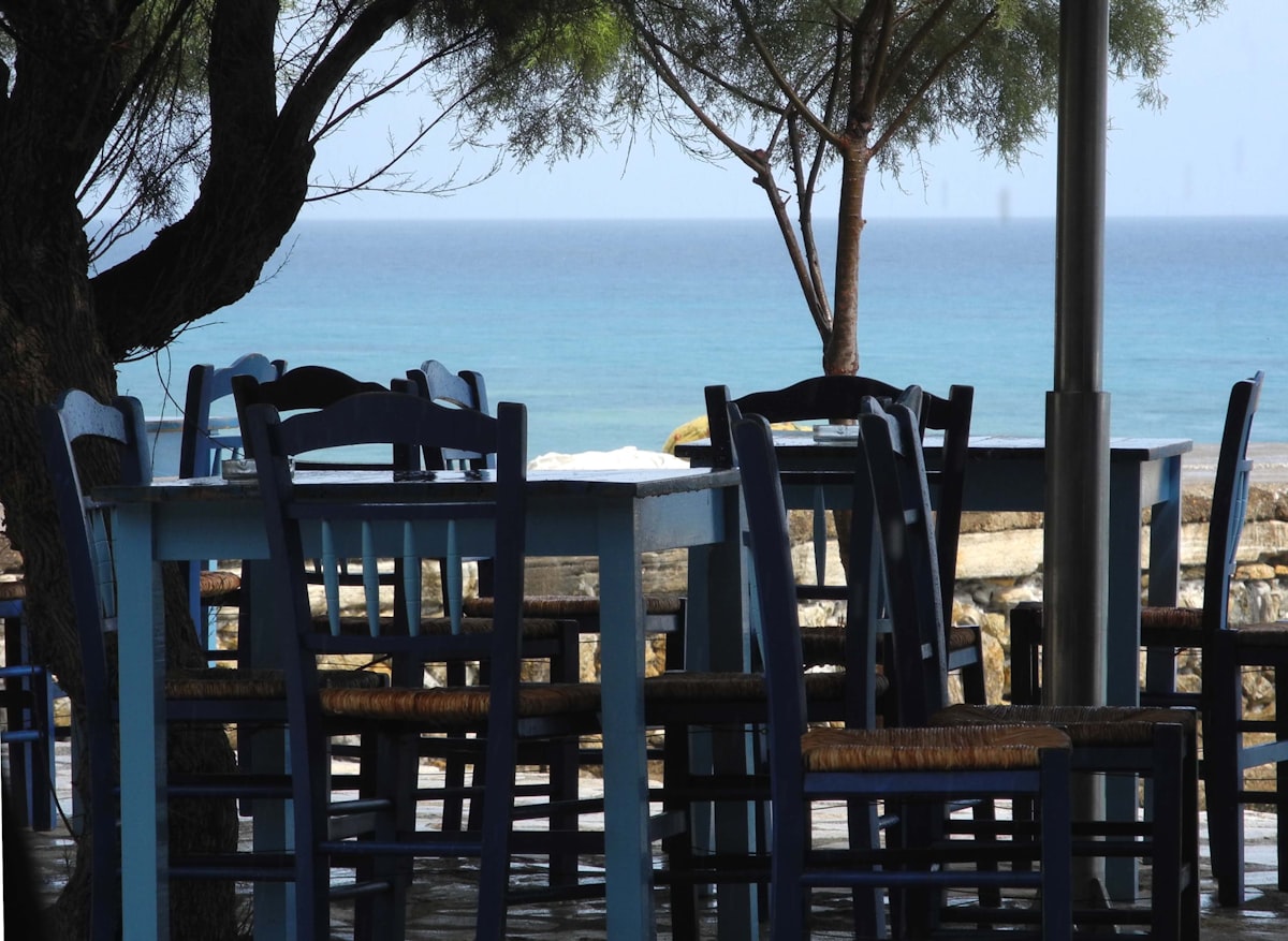 a table and chairs with a view of the ocean