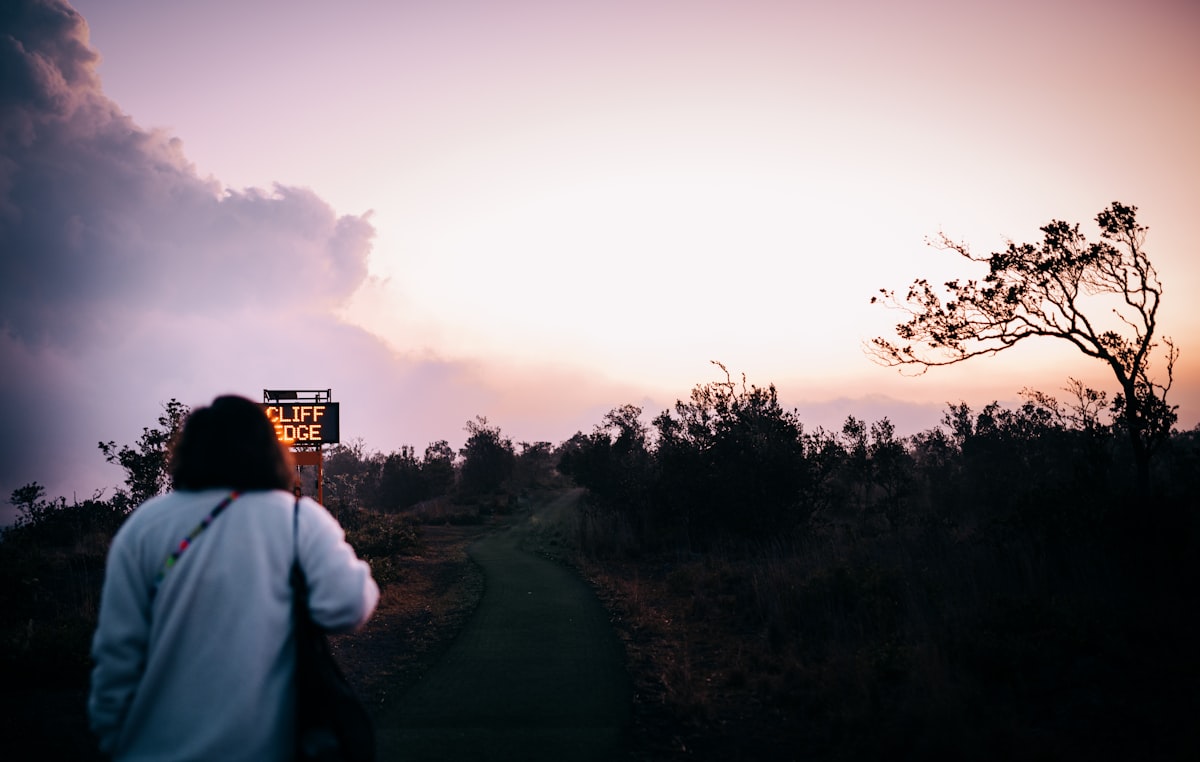 man in white shirt standing on road during sunset