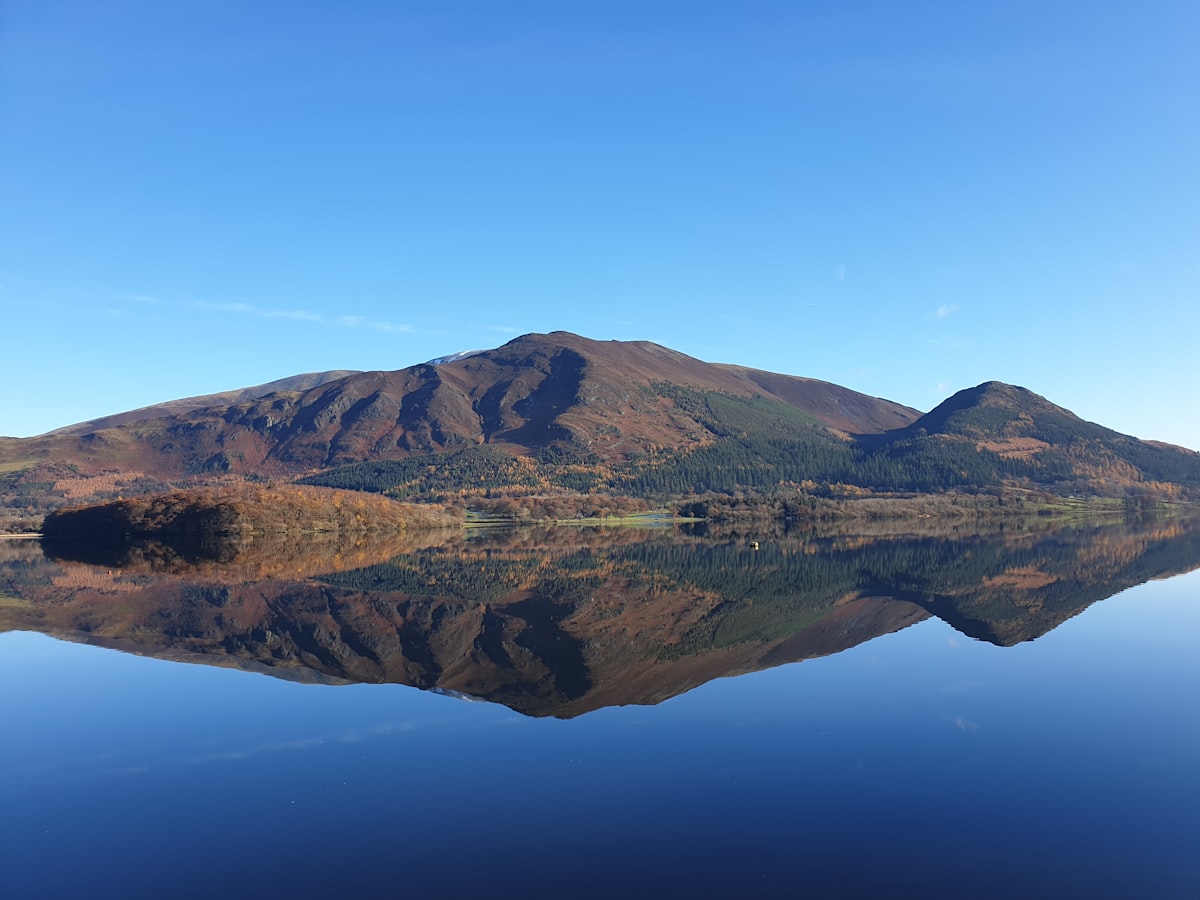 brown and green mountain beside body of water during daytime