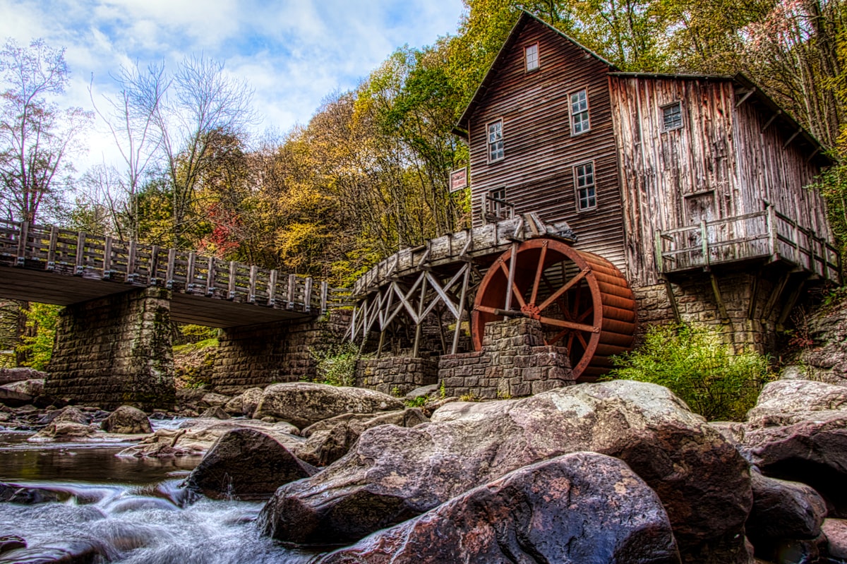 Old wooden mill with water wheel by rocky stream