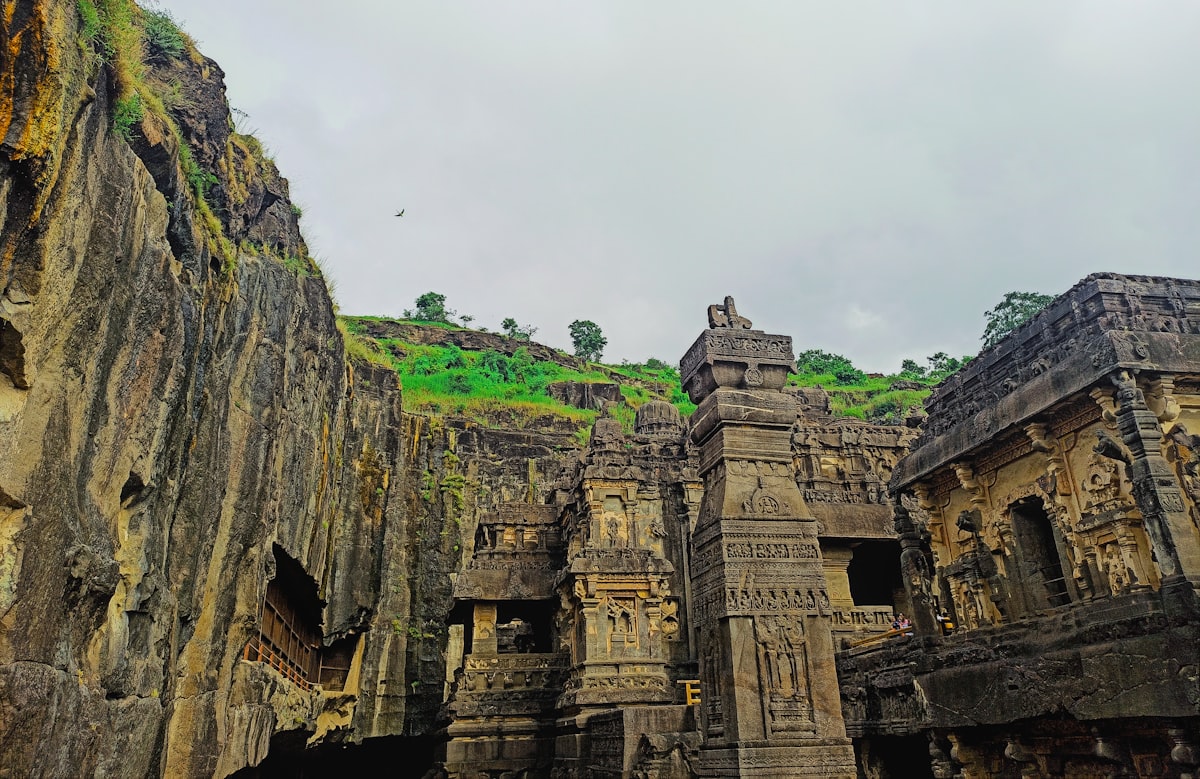 a group of stone structures with a green hill in the background