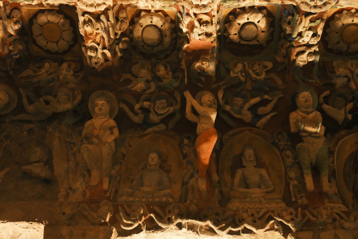 Ancient carved stone frieze with figures and floral motifs.