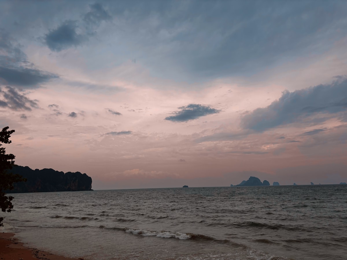 A view of a beach at sunset with a boat in the distance
