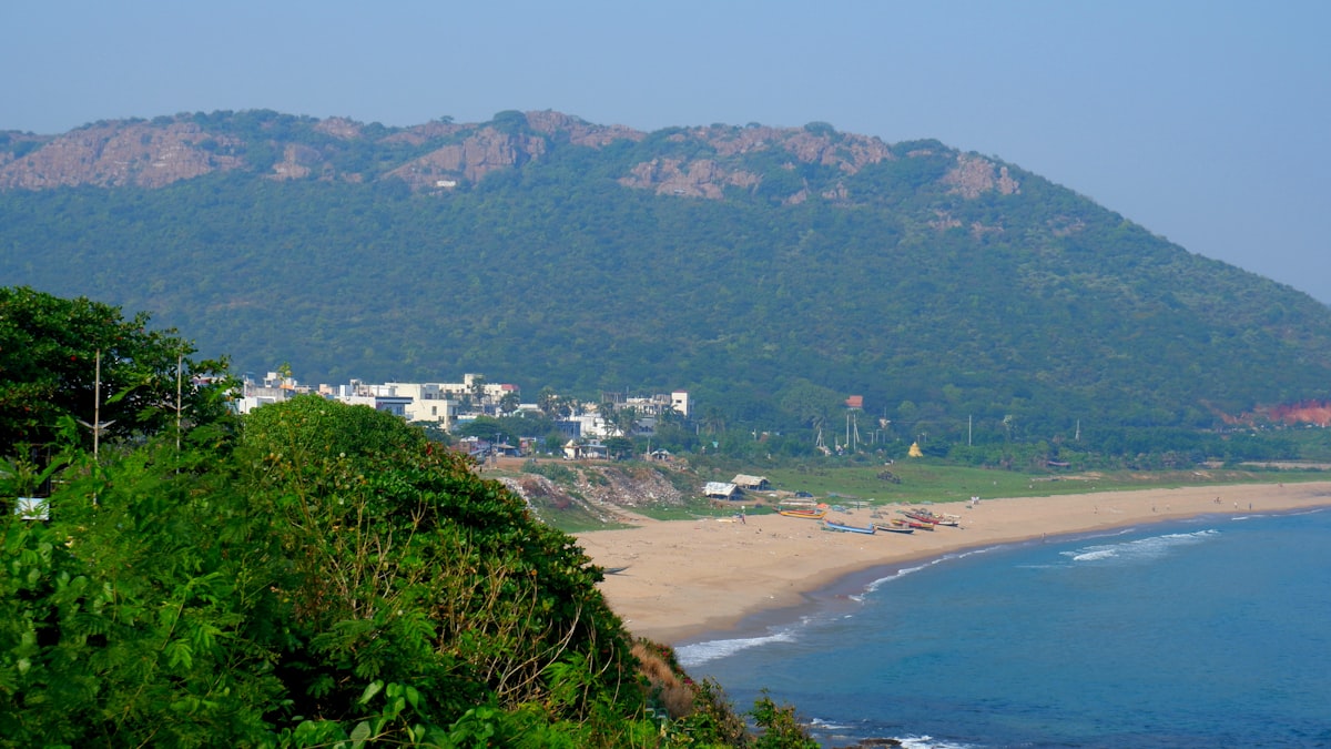 A beach scene with a mountain and buildings.