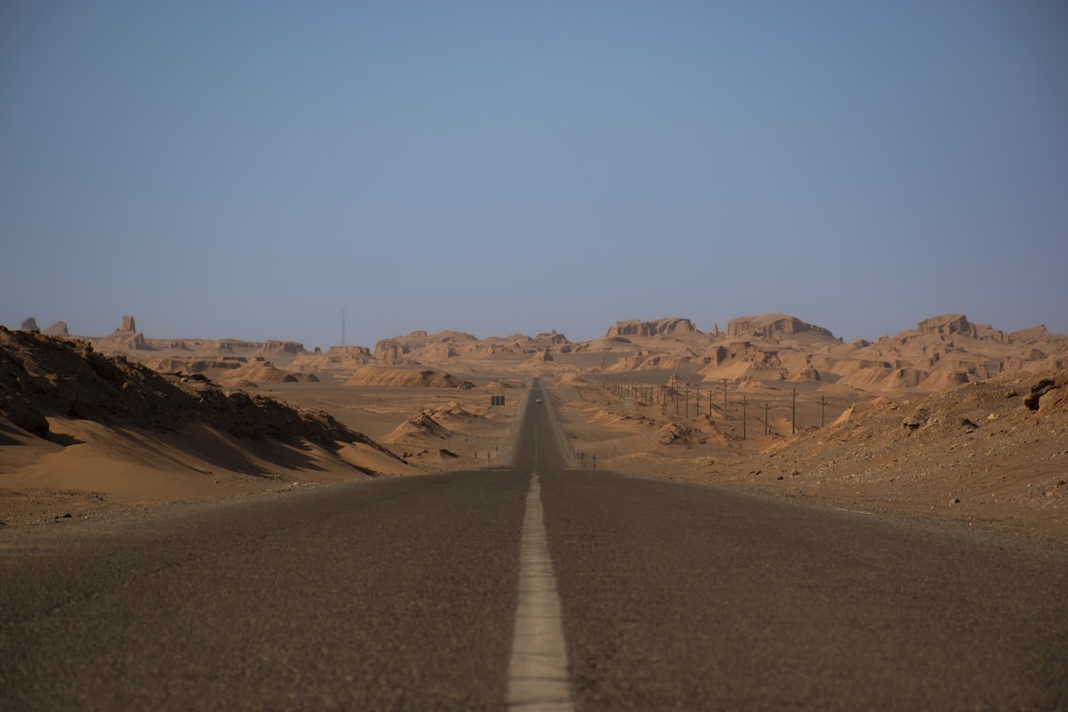 Long desert road stretching towards rocky formations