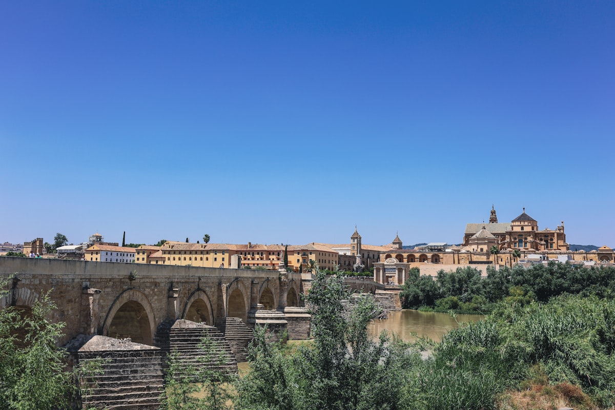 Roman bridge and historic buildings under a clear blue sky.
