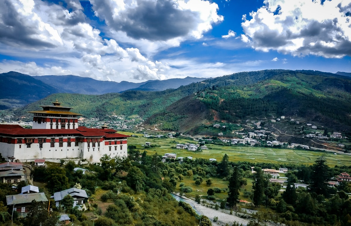 a large white building sitting on top of a lush green hillside