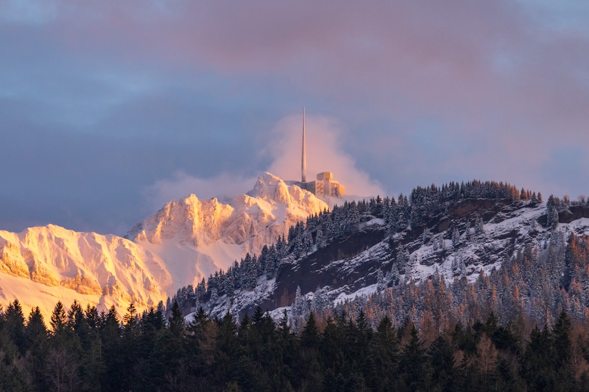 a mountain covered in snow with a radio tower on top of it