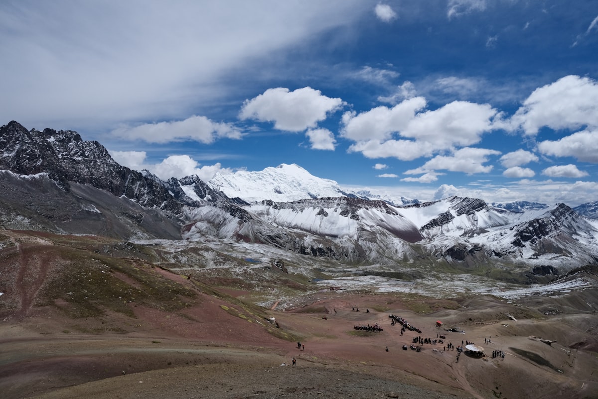 Snow-capped mountains under a cloudy blue sky