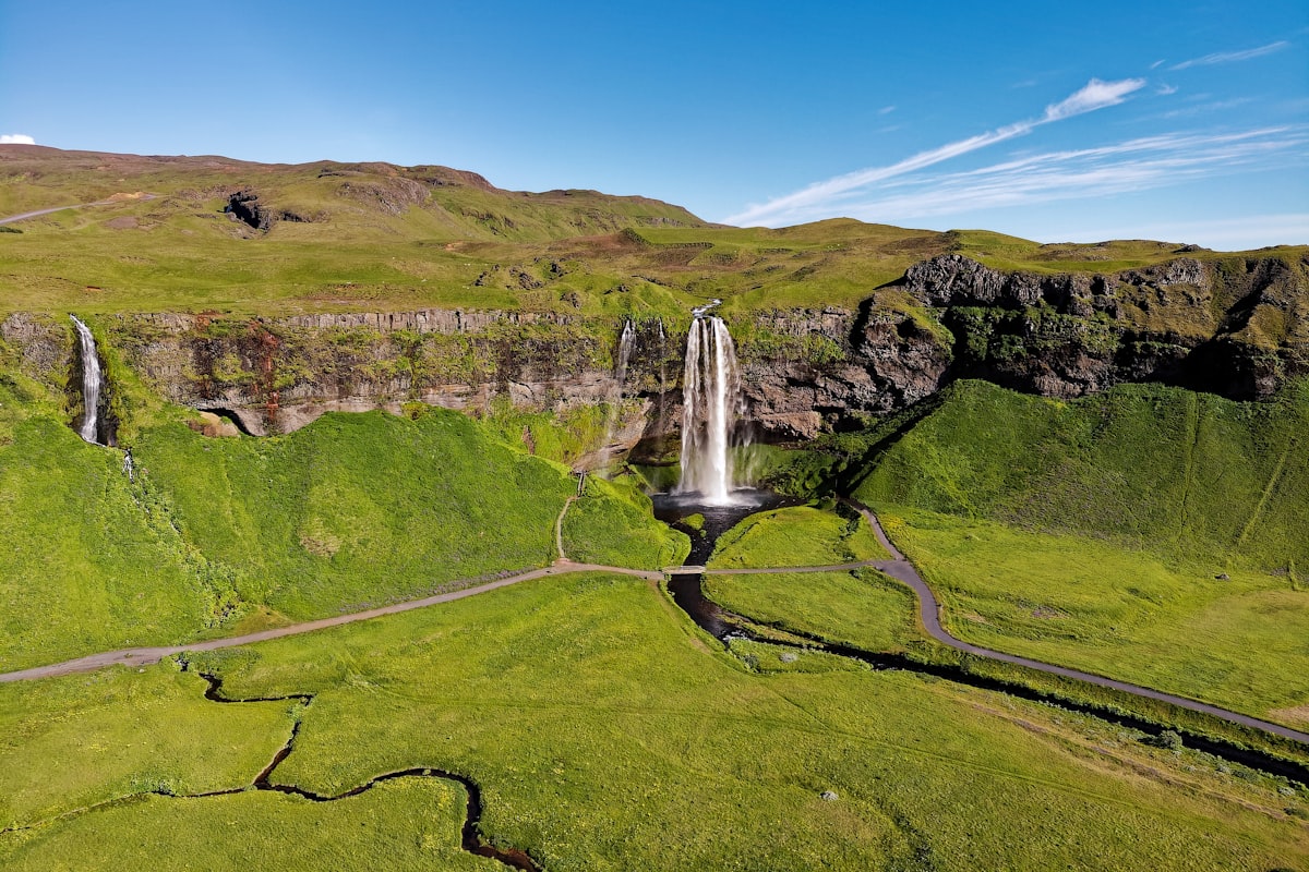 waterfalls on green grass field during daytime