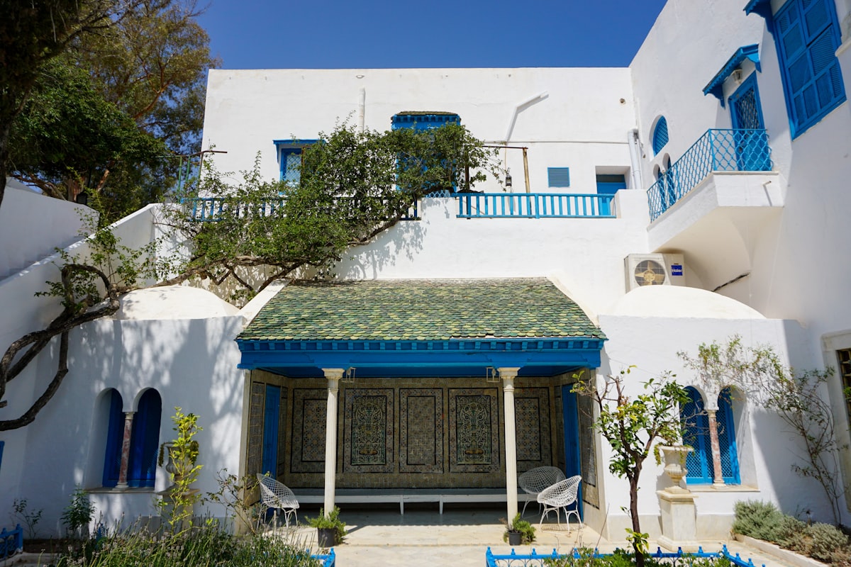 A white house with blue shutters and a green roof