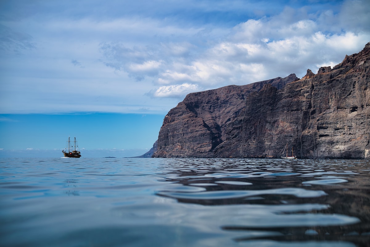 a boat in the water by a cliff