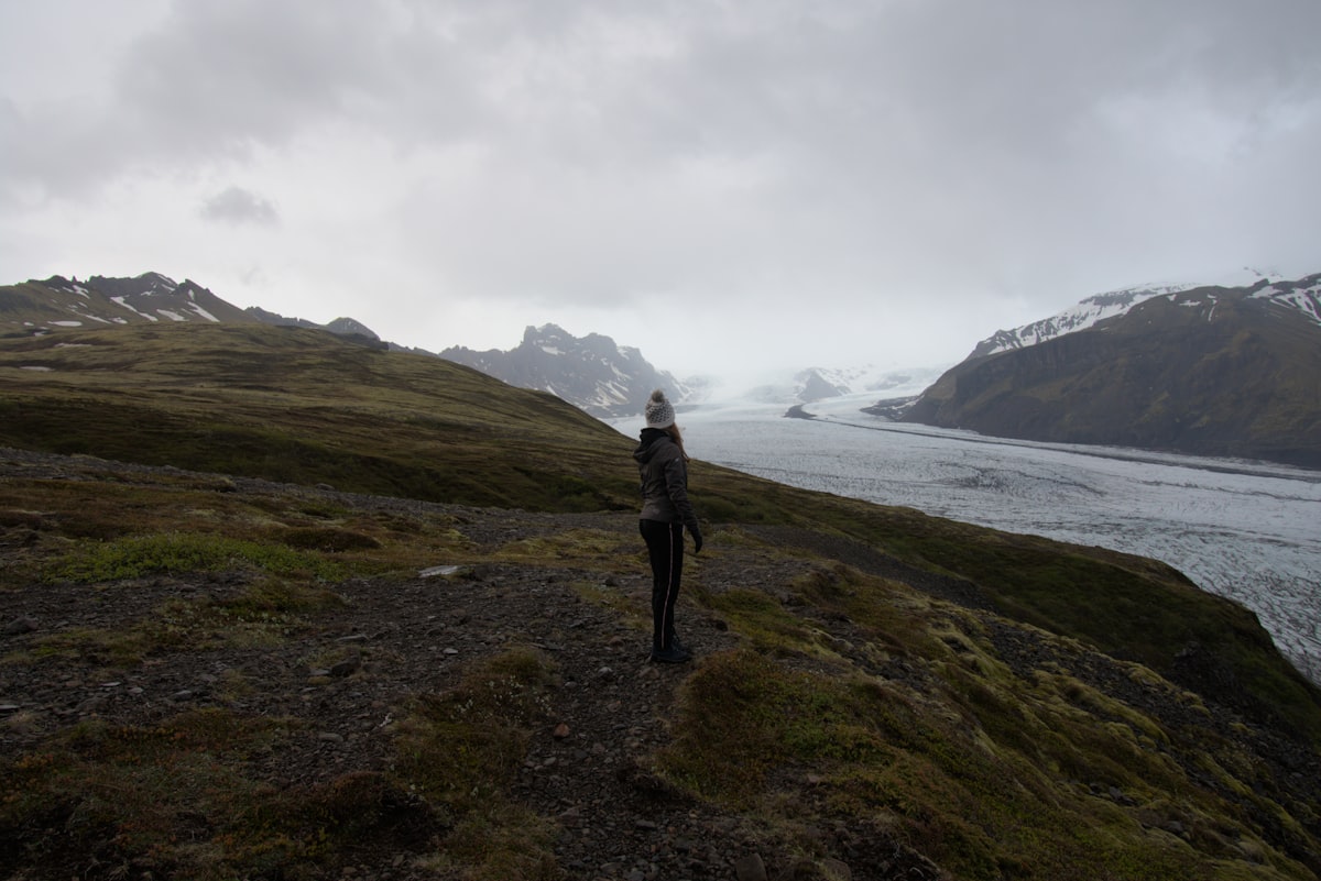 a woman standing on top of a lush green hillside