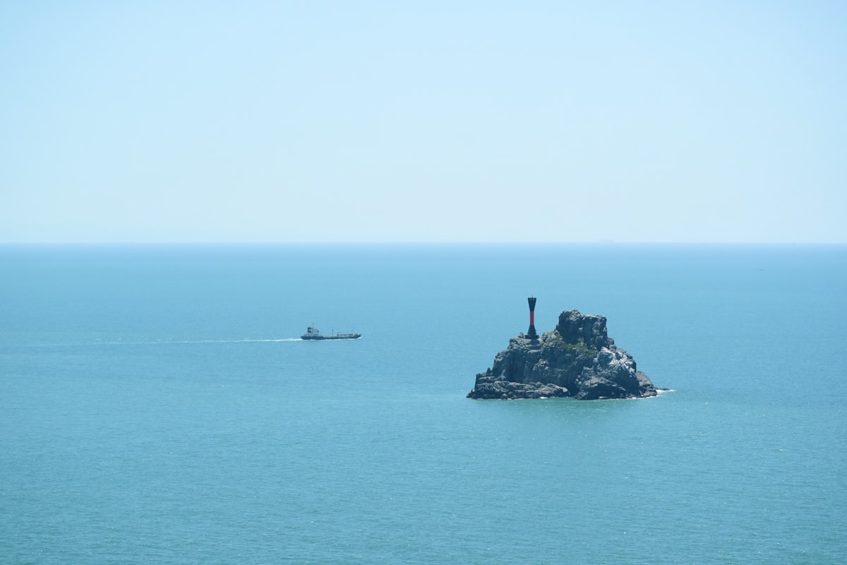 person standing on rock formation in the middle of the sea during daytime