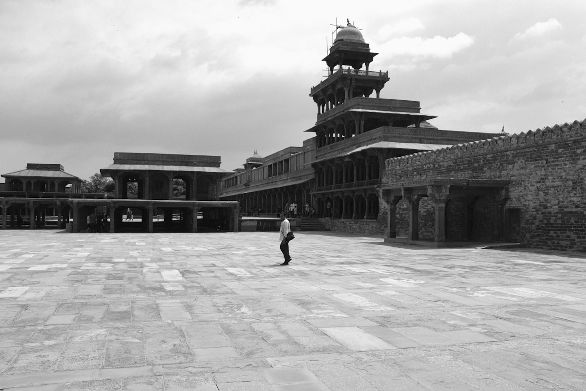 A black and white photo of a person walking in a courtyard