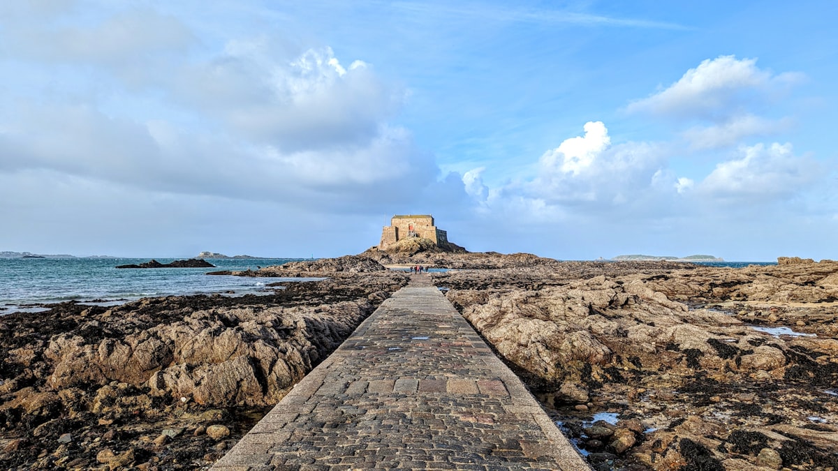 A stone walkway leading to the ocean on a cloudy day