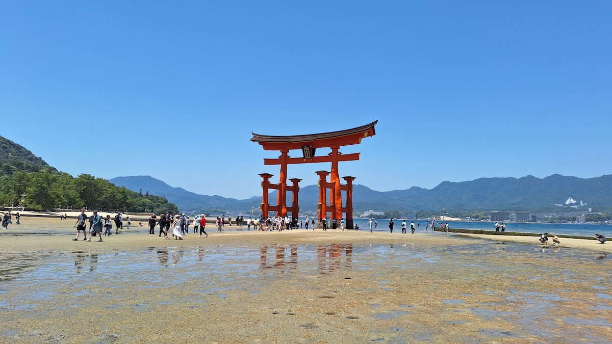 A large red torii gate on a sandy beach.
